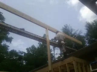 Carpenter setting a ridge beam over a new addition frame — Ice Dam Removal by Roofing Brothers in Oriska