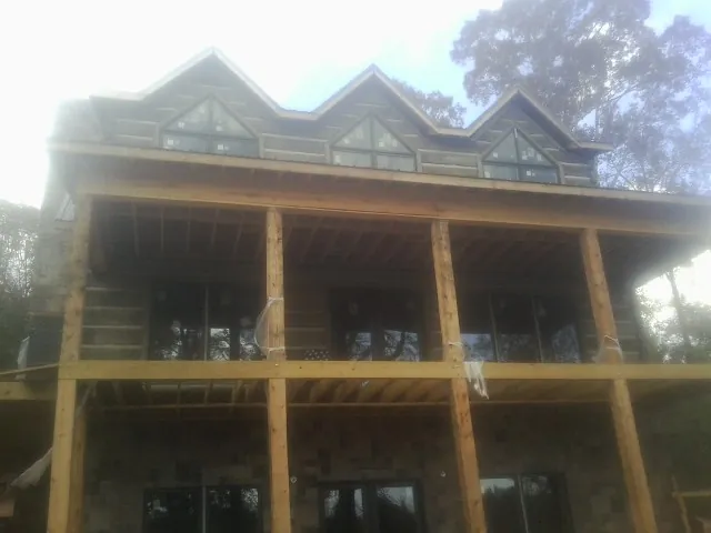 Dormers and porch framing on a large log home under construction — Roof Coating work by our crew in Oriska