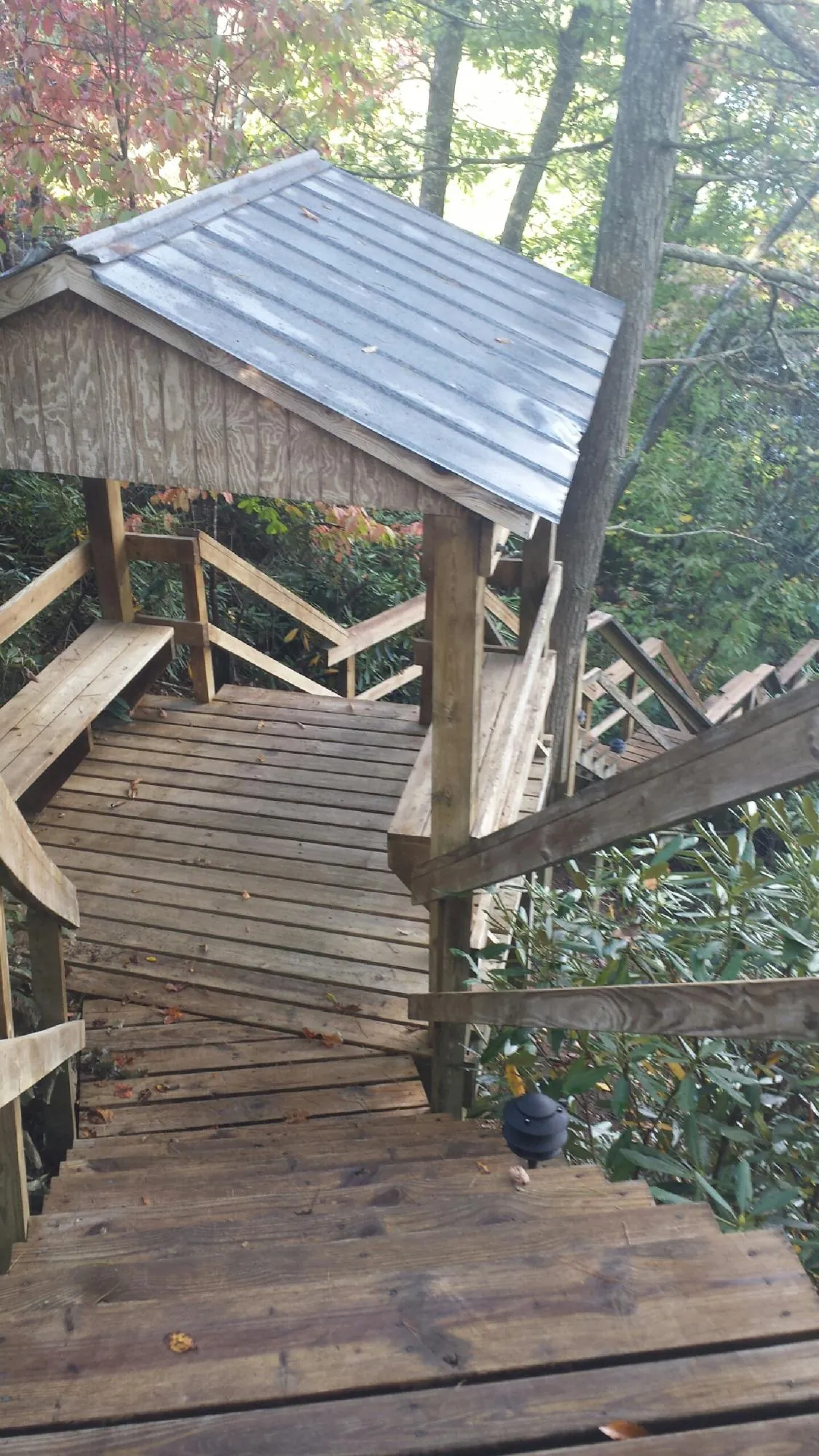 Metal roofed shelter over wooden steps on a wooded walkway — Skylight Repair & Installation work by our crew in Oriska