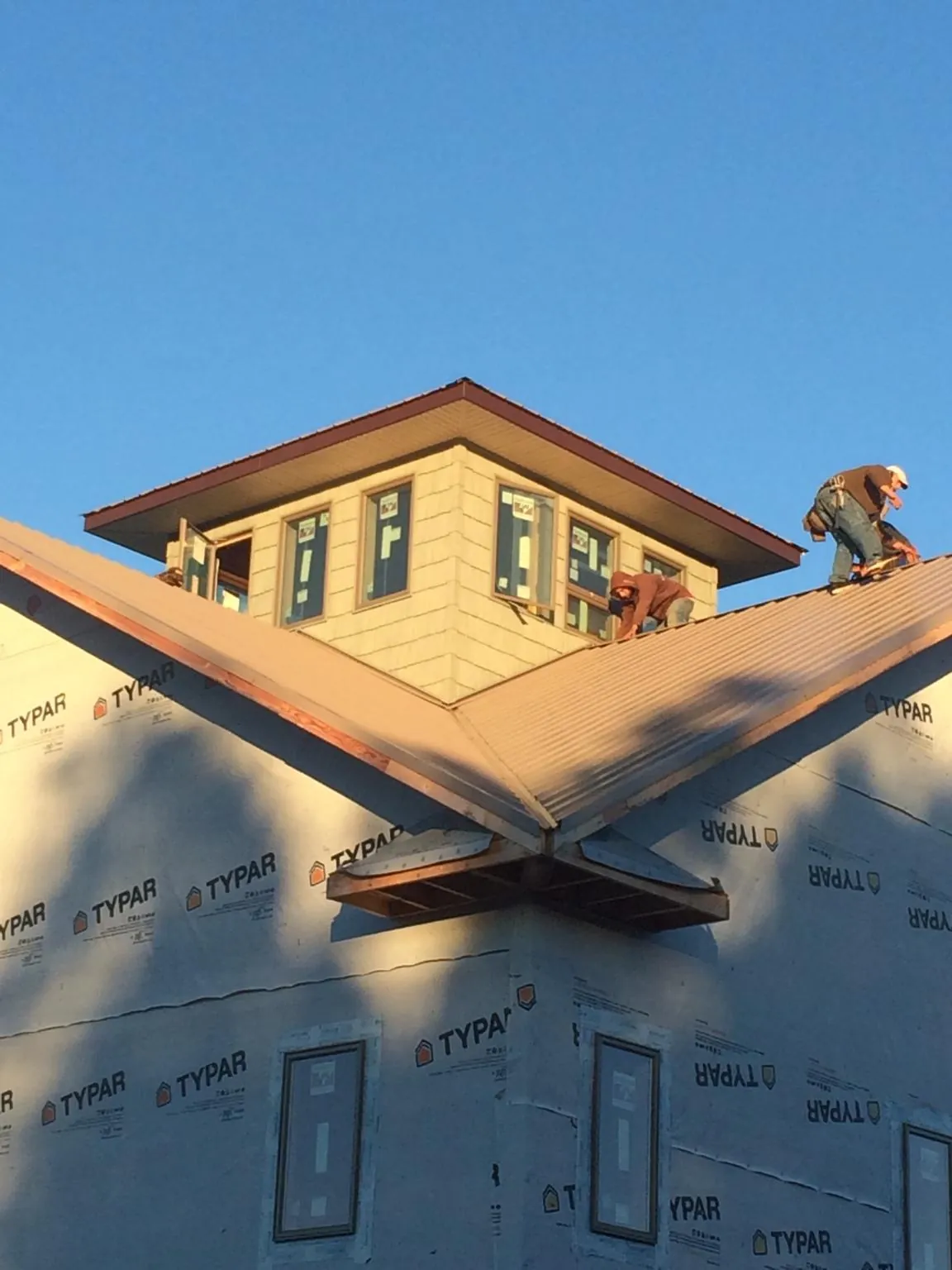 Roofers working around a rooftop cupola on a new metal roof at sunset — Roof Waterproofing in Oriska by Roofing Brothers